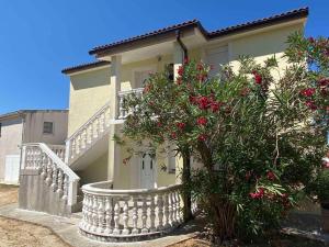 una casa bianca con una scala bianca e fiori di Apartmani Vlahek Stara Novalja a Stara Novalja