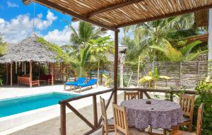 a patio with a table and chairs next to a swimming pool at Maracuja villa Zanzibar in Bwejuu