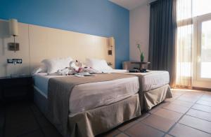 ein Hotelzimmer mit zwei Betten, auf denen Stofftiere liegen in der Unterkunft Hotel Albaida Nature in Mazagón