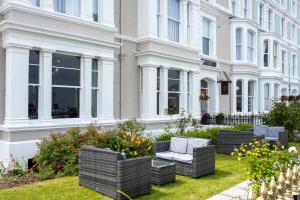 a row of wicker chairs on a lawn in front of a building at The Cae Mor Hotel in Llandudno