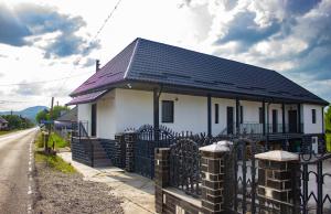 a white house with a black roof behind a fence at Ami's Home in Săpânța