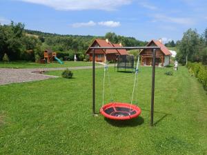 a playground with a swing in a yard at Domki U Tadzia 603-425-844 in Polańczyk