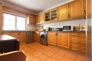 eine Küche mit Holzschränken und einer Waschmaschine in der Unterkunft Casa Macau T4 com piscina in Pousadas