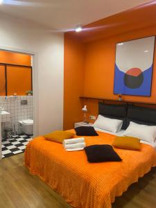a bedroom with a bed with orange walls and a bathroom at Vere Side Hotel in Tbilisi City