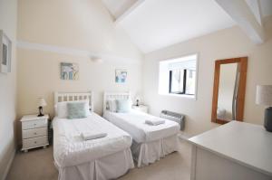 two beds in a white room with a mirror at Dairy Cottage in Shaftesbury