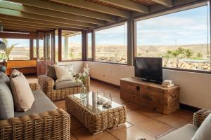 a living room with a television and a couch and chairs at Casa Amanecer in Haría