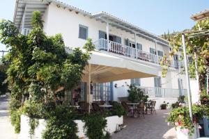 a white building with a balcony and tables and chairs at Elena Rooms in Agios Nikitas