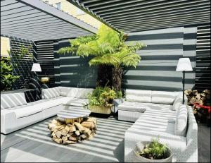 eine Terrasse mit weißen Sofas und einer Palme in der Unterkunft Stunning Designer House, Fantastic City Location - Cambridge Homehost in Cambridge