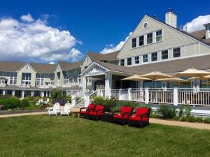 a large house with red chairs and umbrellas at Inn By the Sea in Cape Elizabeth