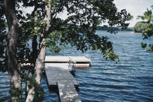 a dock on a lake with a boat in the water at Pakaso sodyba in Kirdeikiai