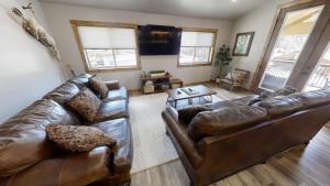 a living room with leather couches and a tv at Red River Retreat - WiFi - Hot Tub - Fireplace - Washer - Dryer - Grill in Red River