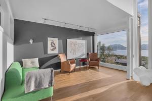 a living room with a green couch and chairs at Funkisvilla med panoramautsikt in Tromsø