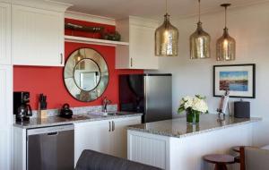 a kitchen with white cabinets and a red wall at Inn By the Sea in Cape Elizabeth