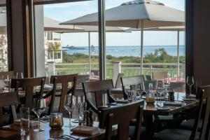 a restaurant with tables and chairs with a view of the ocean at Inn By the Sea in Cape Elizabeth