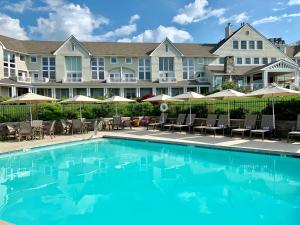 a pool at a resort with chairs and umbrellas at Inn By the Sea in Cape Elizabeth