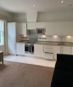 una cucina con mobili bianchi e un forno a piano cottura di 3 Central Bedroom flat a Cambridge