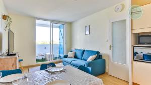 een woonkamer met een blauwe bank en een tafel bij La Goelette 30 in Saint-Hilaire-de-Riez