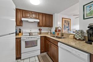 cocina con armarios de madera y horno de fogón blanco en St. Augustine Ocean Racquet Club Unit 3303, en St. Augustine