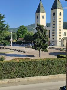 a church with two towers with a tree in front at Rooms Zdravko and Nevenka Cilic in Međugorje