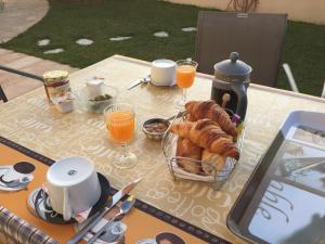 un tavolo con un cesto di croissant e bicchieri di succo d'arancia di Chambre La Poulpiquet ad Ars-en-Ré