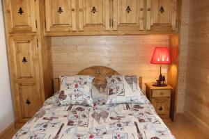 1 dormitorio con 1 cama con pared de madera en Le Chalet d'Ulysse, en Arâches-la-Frasse