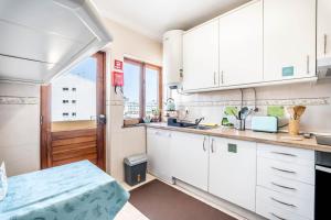 a kitchen with white cabinets and a window at On the way!* in Portimão