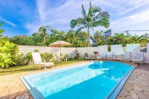 a swimming pool with chairs and an umbrella at Piscina e 3 dorm a 150 m de Camburizinho in Camburi