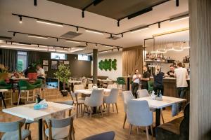 a restaurant with white tables and chairs and people at Hotel THR Center in Curtea de Argeş