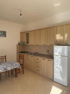 a kitchen with wooden cabinets and a white refrigerator at Villa Pams in Baks-Rrjoll +10 photos