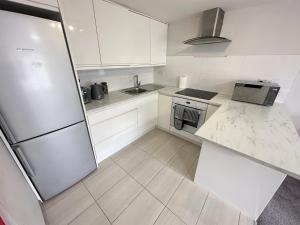 a white kitchen with a refrigerator and a sink at Horizon House, Modern 1-Bedroom, Netflix, WiFi, Free Parking, Oxford in Oxford