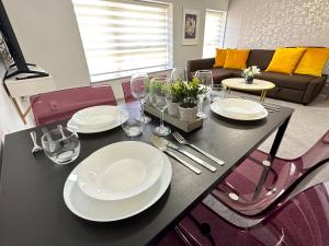 a dining room table with plates and wine glasses at Horizon House, Modern 1-Bedroom, Netflix, WiFi, Free Parking, Oxford in Oxford