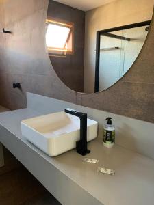 a bathroom counter with a sink and a mirror at Paraíso Capitólio Suítes Pousada in Capitólio