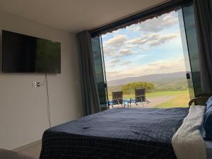 a bedroom with a bed and a large window at Casa vista da serra in São João del Rei +9 photos