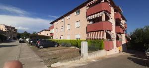 a building with cars parked in front of it at Apartman Romina in Pula