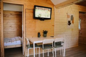 a dining room with a table and a tv on the wall at Domki Marianówka Wieżyca in Potuły