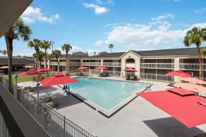 a swimming pool with red umbrellas and a hotel at 11 Condo-Hotel With Double Bed And Community Pool Miles From Disney! in Kissimmee
