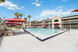 a large swimming pool with red umbrellas in a resort at 11 Condo-Hotel With Double Bed And Community Pool Miles From Disney! in Kissimmee