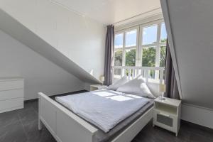 ein weißes Schlafzimmer mit einem Bett und einem Fenster in der Unterkunft Ferienhaus Natura Ideal für Urlaub & Business, Küche, WLAN, Parkplatz in Rhauderfehn