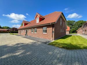 ein Backsteinhaus mit rotem Dach in der Unterkunft Ferienhaus Natura Ideal für Urlaub & Business, Küche, WLAN, Parkplatz in Rhauderfehn