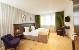 ニュルンベルクにあるホテル ハウザー ブティックのホテルルーム ベッド1台&紫色の椅子2脚付