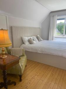 a bedroom with a bed and a chair and a lamp at Farm Stay B & B in Annerstad