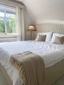 a bedroom with a large white bed with a blanket on it at Farm Stay B & B in Annerstad