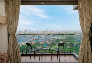 Zimmer mit 2 Stühlen und einem großen Fenster in der Unterkunft Freesia Residency By Express Inn - Navi Mumbai in Navi Mumbai