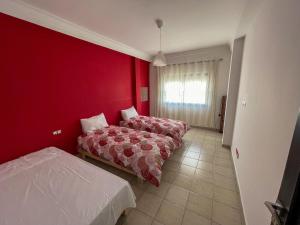 una camera da letto con due letti e una parete rossa di Apartamento Ajanif Terraza Centro Martil Miramar 100 Metros playa a Martil