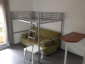 a bunk bed in a room with a couch and a table at Studio avec balcon - Plage à 10min à pied in Le Pradet