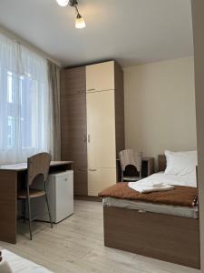 a bedroom with a bed and a desk and chairs at Хостел Атлас - Hostel Atlas in Blagoevgrad