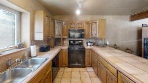 a kitchen with wooden cabinets and a stove and a sink at River Ritz - Pet Friendly - WiFi - Near the Ski Area - Fireplace - On the River - Washer - Dryer - in Red River