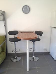 a table with two stools and a clock on the wall at Studio avec balcon - Plage à 10min à pied in Le Pradet