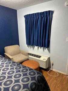 a bedroom with a bed and a chair and a window at Tanglewood Motel in Frederick +1 photo