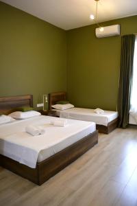 two beds in a room with green walls at Hotel Tabernei in Tbilisi City